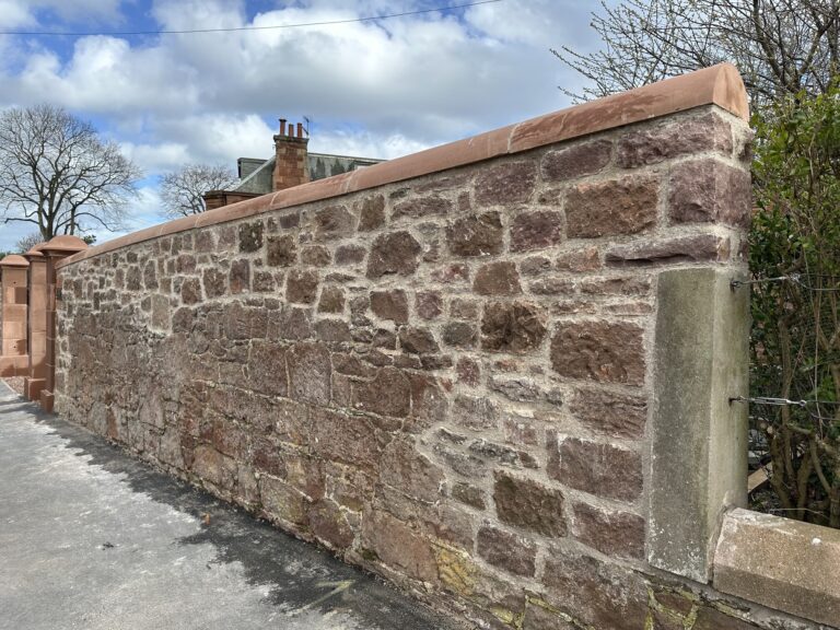 Newly built rubble stone boundary wall with sandstone coping