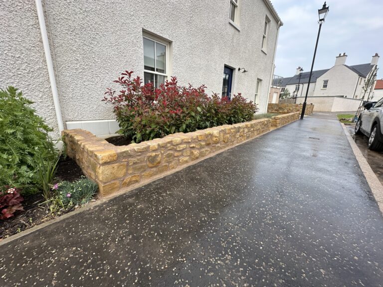 Low stone garden wall alongside a newly surfaced driveway