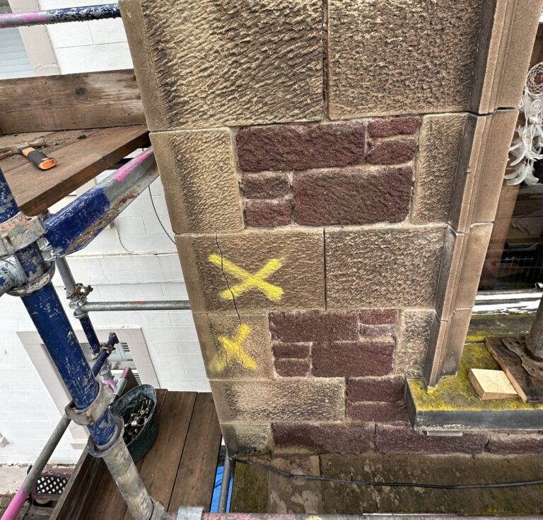 Sandstone pier marked for repair on a building at The Square