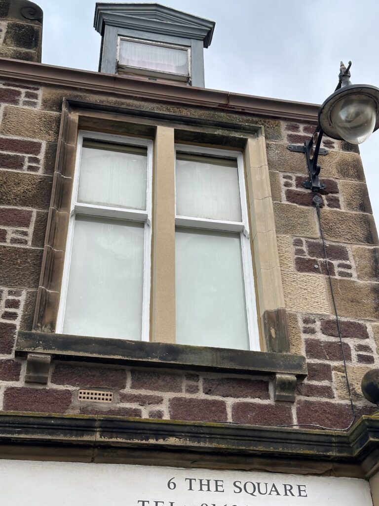 Sandstone window surround above a shopfront at 6 The Square
