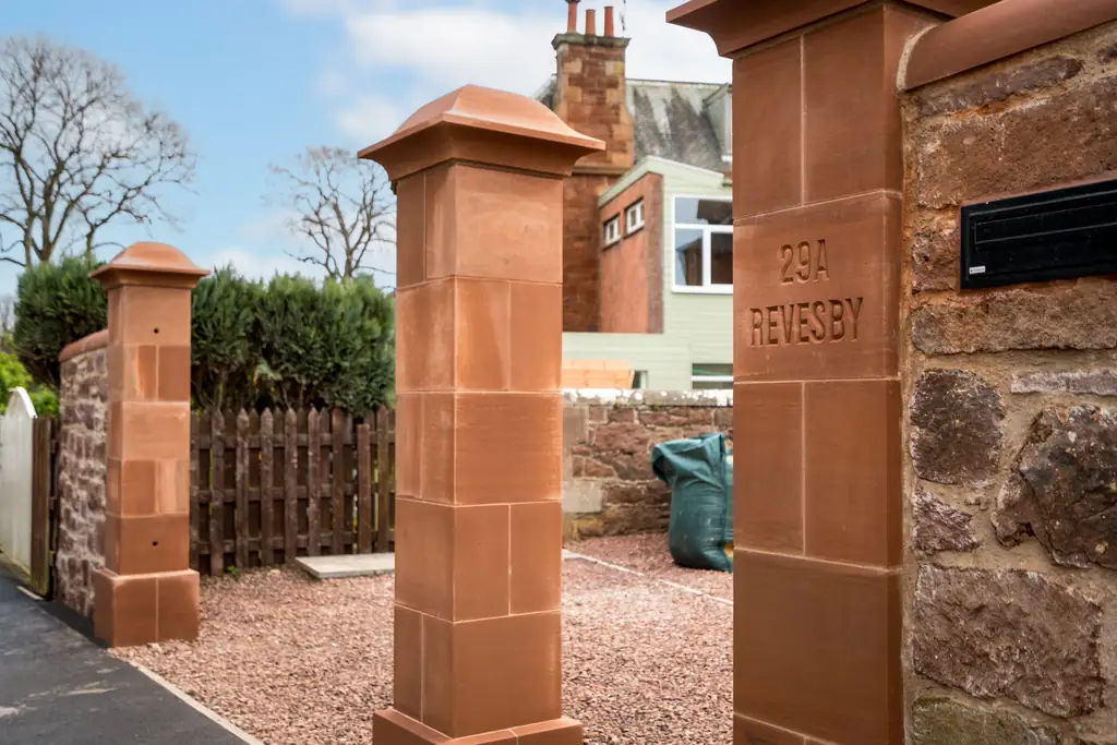 Red sandstone gate pillars and stone boundary wall