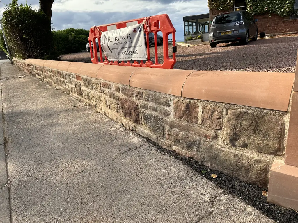 Repaired stone boundary wall with new sandstone coping