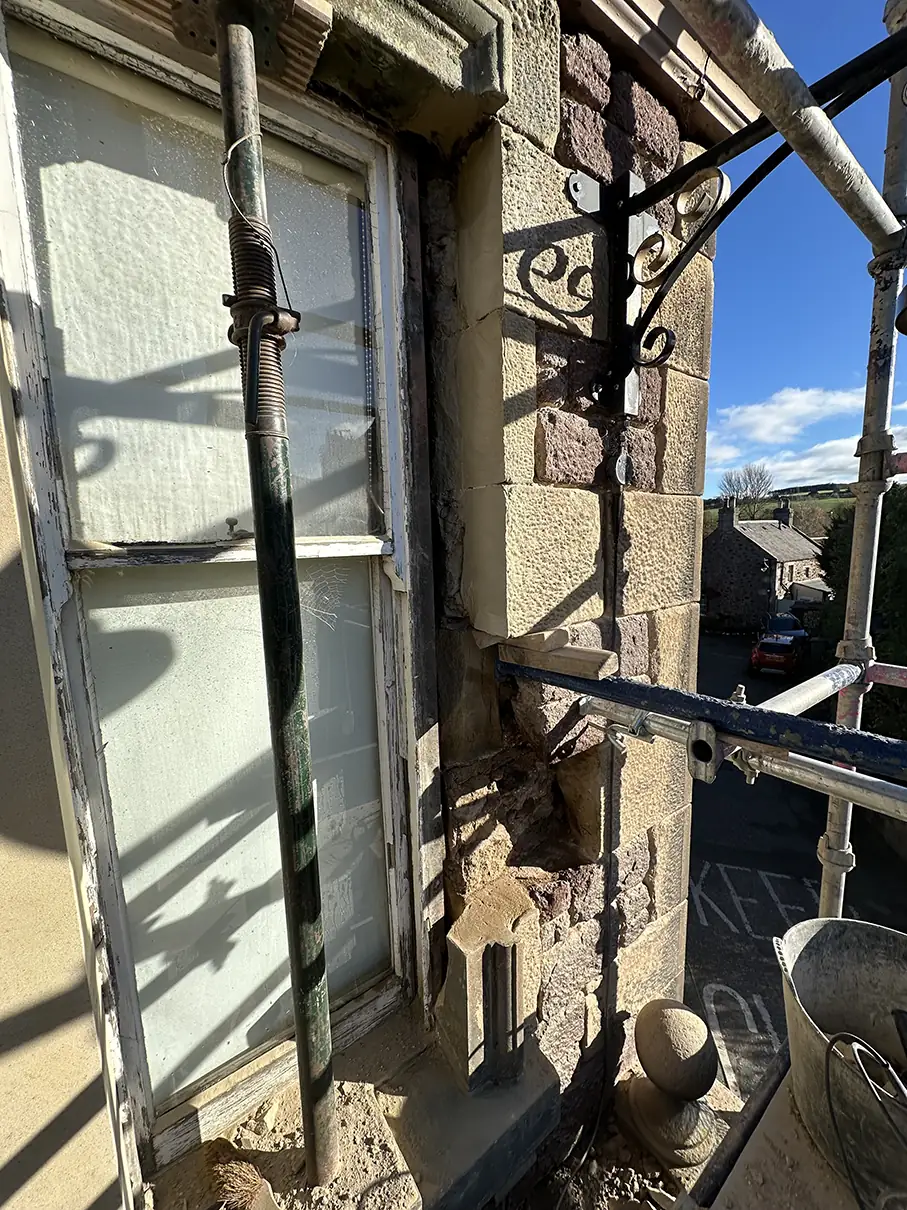 Sash window and eroded sandstone surround under scaffolding at The Square