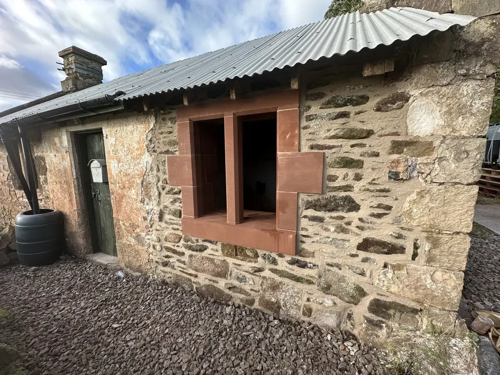 Restored rubble stone cottage with red sandstone window surrounds at West Lodge