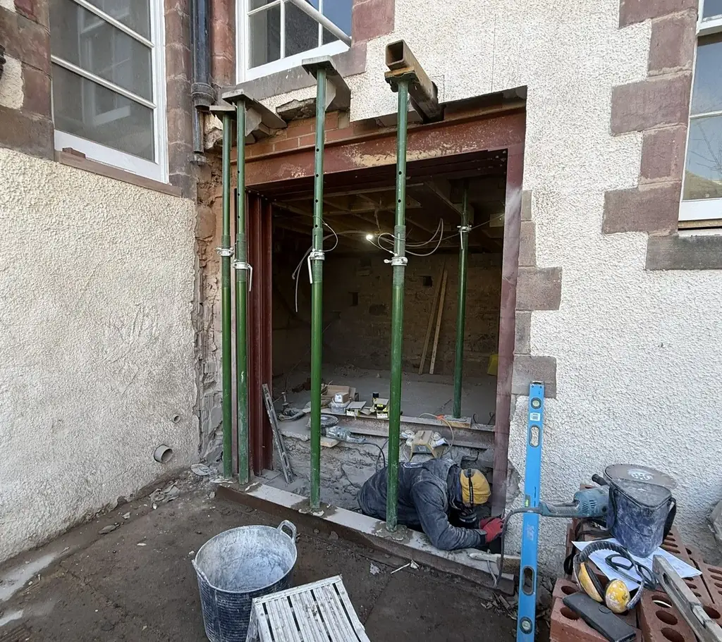 Structural alteration in progress with temporary supports in a stone wall